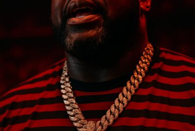 Shaquille O'Neal in red lighting wearing diamond chain conversing with elderly couple