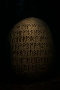 Ancient runic inscriptions carved into a large granite boulder illuminated in a dark Ontario forest