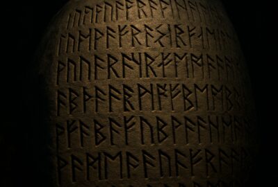 Ancient runic inscriptions carved into a large granite boulder illuminated in a dark Ontario forest