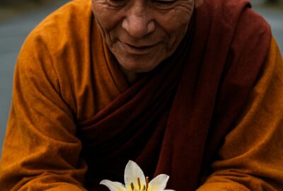 Buddhist monk smiling as young child offers white and yellow flower bouquet roadside