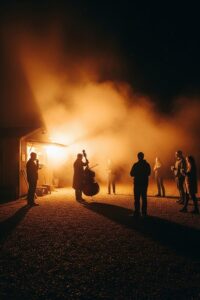 Classical musician playing instrument under late-night highway lights near a BBQ stand