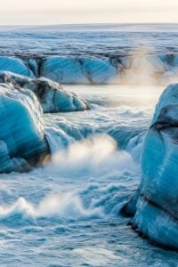 Massive turquoise meltwater river carving through the Greenland ice sheet surface