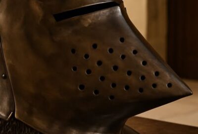 Medieval hounskull bascinet helmet with chainmail aventail resting on dark walnut table