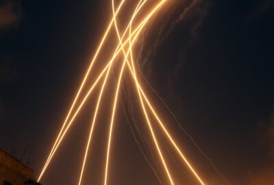 Iron Dome intercept trails streak across a night sky above a glowing city skyline