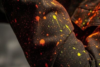 Fluorescent dye splattered across a dark jacket sleeve under bright store lighting