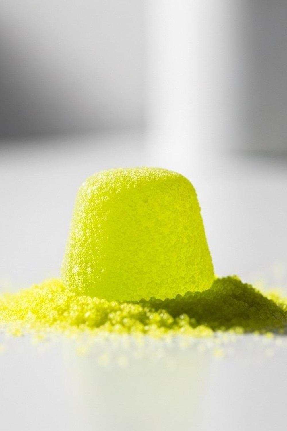 Close-up of bright sour candy dissolving on a tongue, vivid citric crystals visible