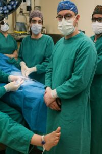 Surgical team in teal scrubs performing procedure under bright OR lighting