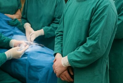 Surgical team in teal scrubs performing procedure under bright OR lighting
