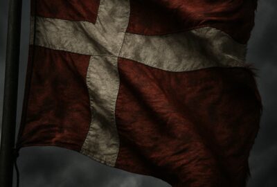 Danish flag flying against a stormy sky symbolizing immigration law controversy in Europe