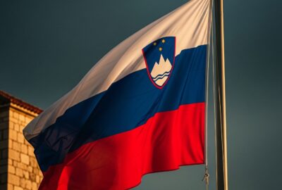 Slovenian flag flying boldly against a dramatic stormy European sky at dusk