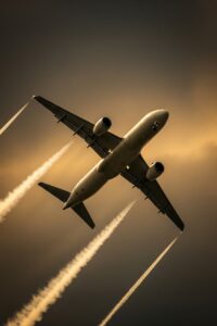 Commercial jet aircraft climbing through dense clouds leaving a visible condensation trail at altitude