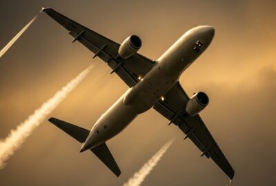 Commercial jet aircraft climbing through dense clouds leaving a visible condensation trail at altitude