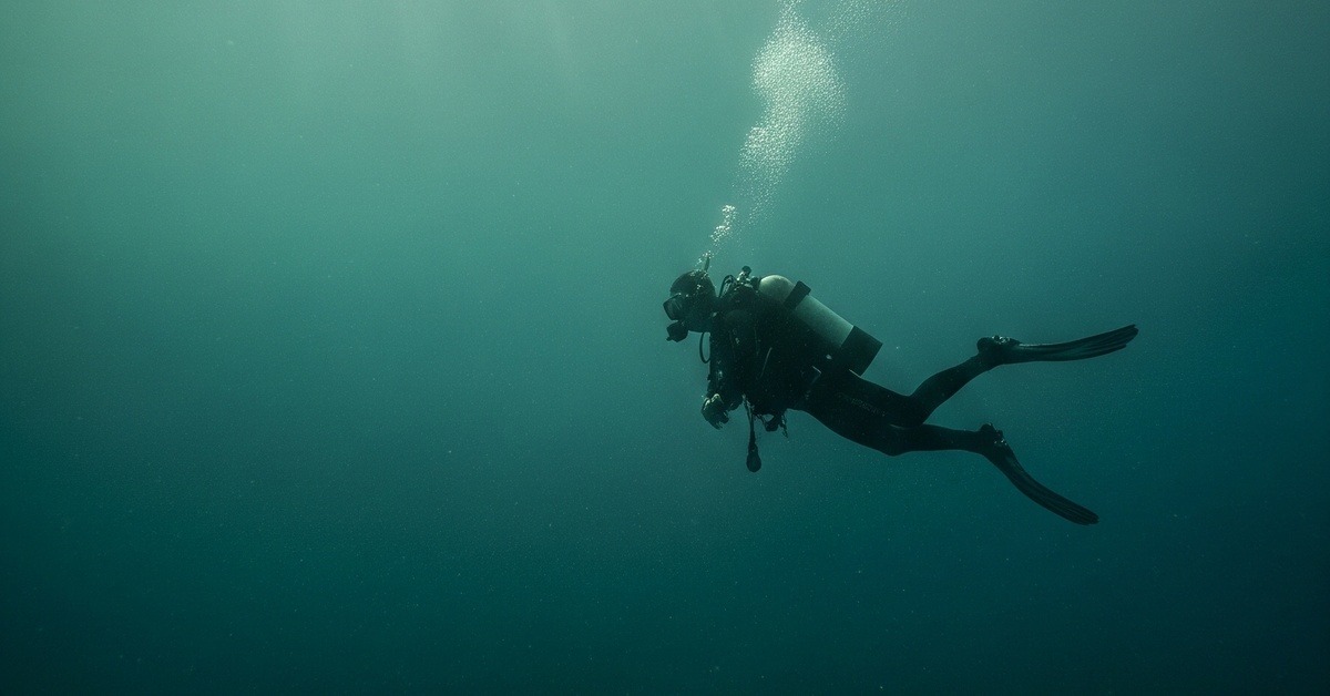 Lone diver silhouetted beneath turbid coastal waters of Sanriku Japan searching ocean floor