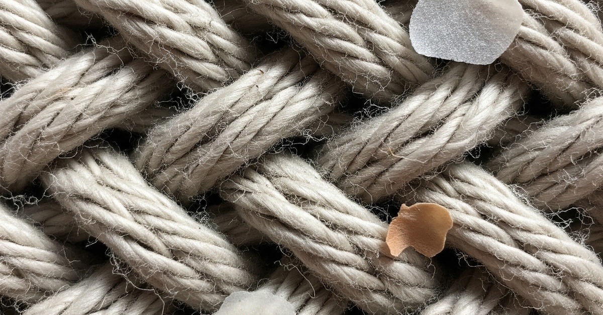 Close-up of woven cotton mattress fabric fibres magnified to show texture and tiny dust particles