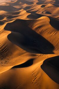 Cross-section of golden Sahara sand dunes above a vast dark reservoir of ancient groundwater sealed in sandstone rock