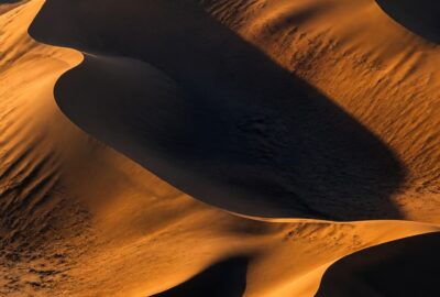 Cross-section of golden Sahara sand dunes above a vast dark reservoir of ancient groundwater sealed in sandstone rock