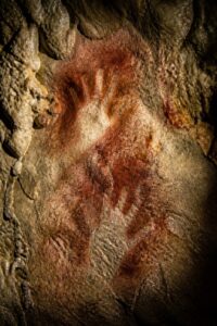 Red ochre negative hand stencils on the wall of El Castillo cave in Cantabria, Spain
