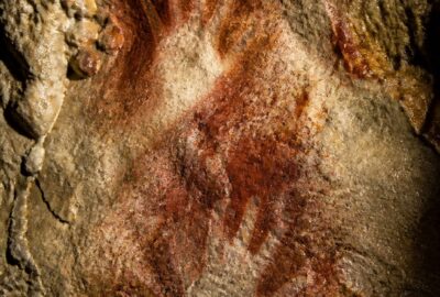 Red ochre negative hand stencils on the wall of El Castillo cave in Cantabria, Spain